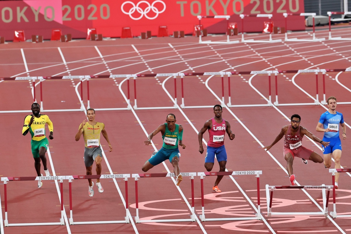 Alison dos Santos corre ao lado de outros atletas em uma prova de 400 metros com barreiras.