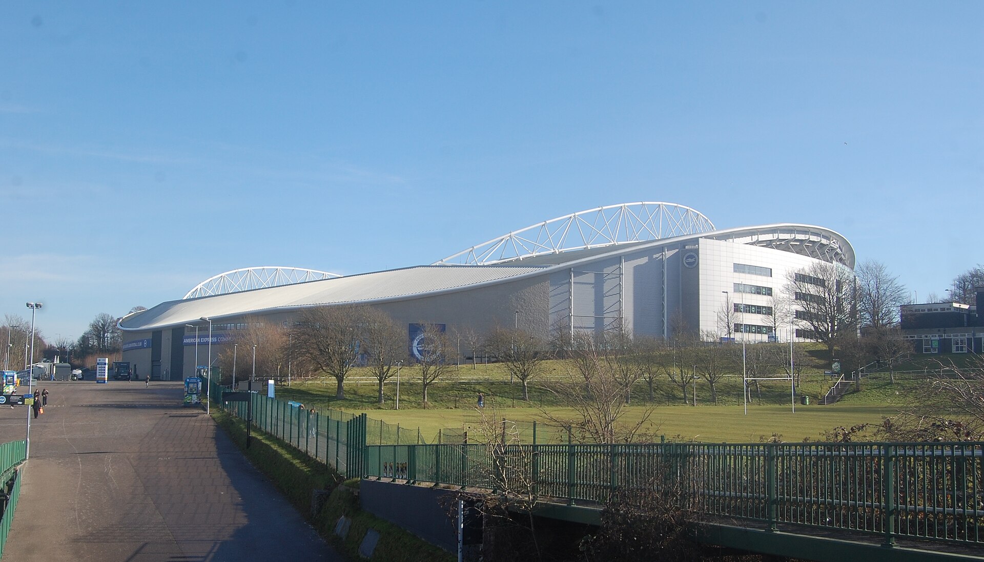 Exterior do Amex Stadium com estrutura coberta e área verde ao redor.