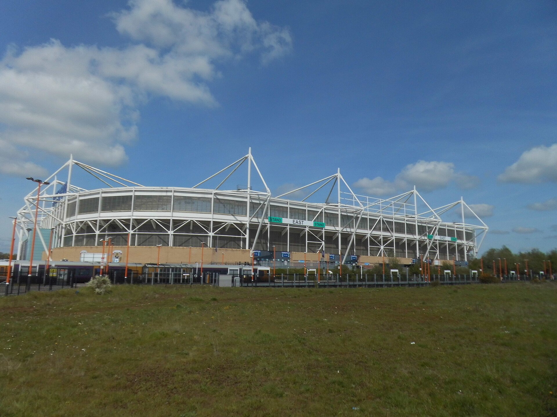 Estrutura externa do Coventry Building Society Arena sob céu azul.