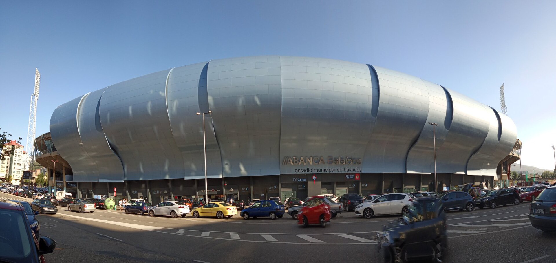 Fachada externa do Estádio Balaídos com veículos e edifícios do entorno urbano.