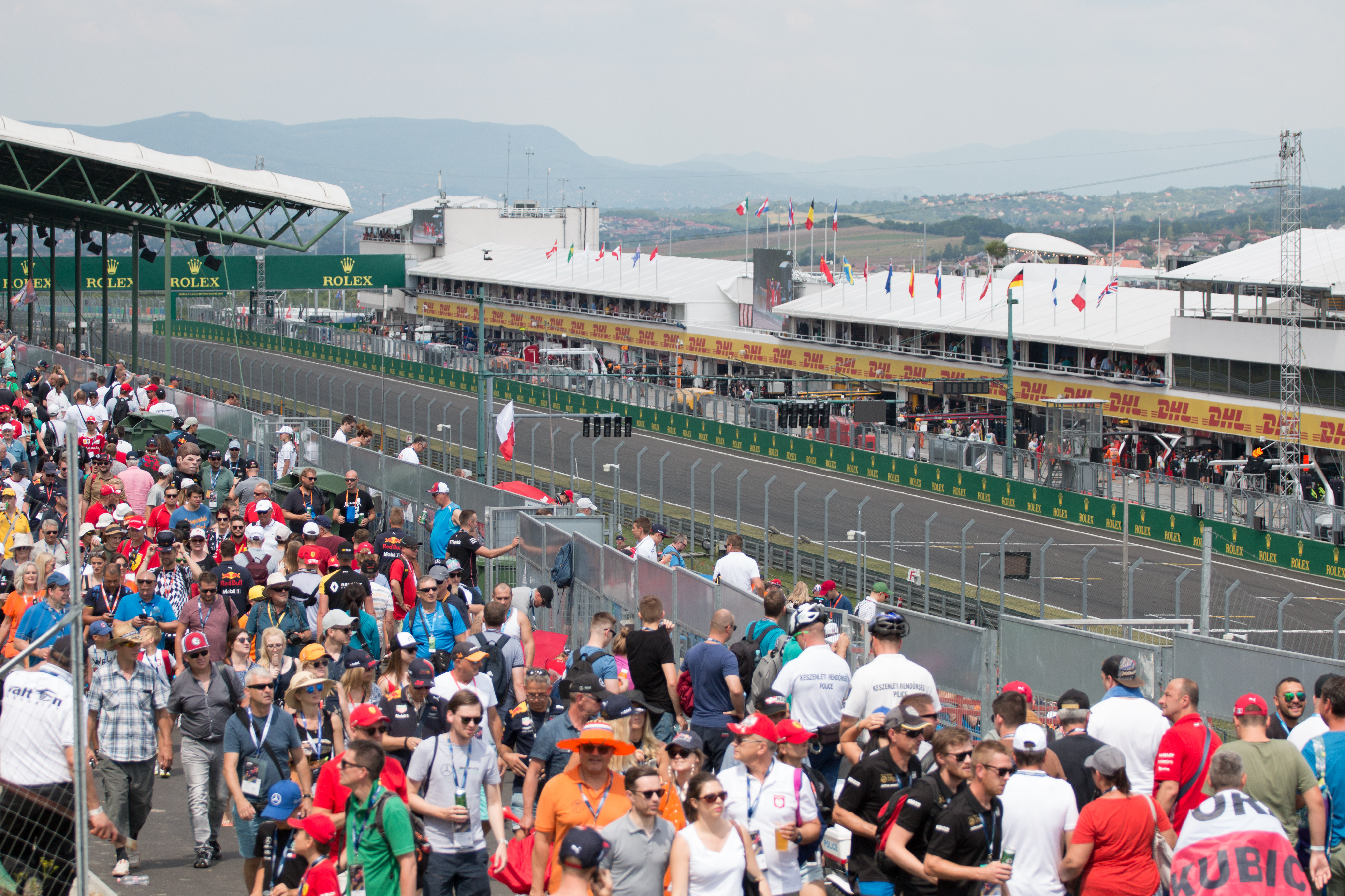 Reta principal e área dos boxes do Hungaroring, com arquibancadas e público em primeiro plano.