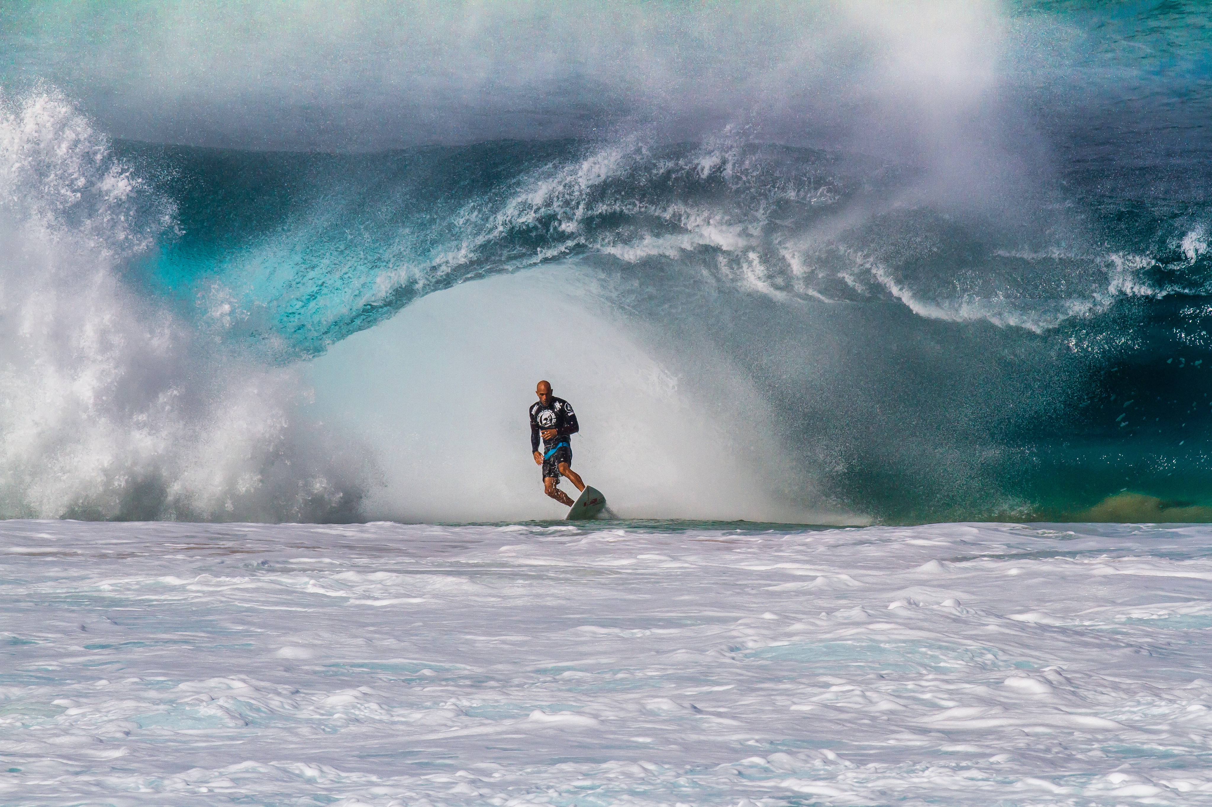 Kelly Slater surfando diante de uma grande seção tubular de onda.
