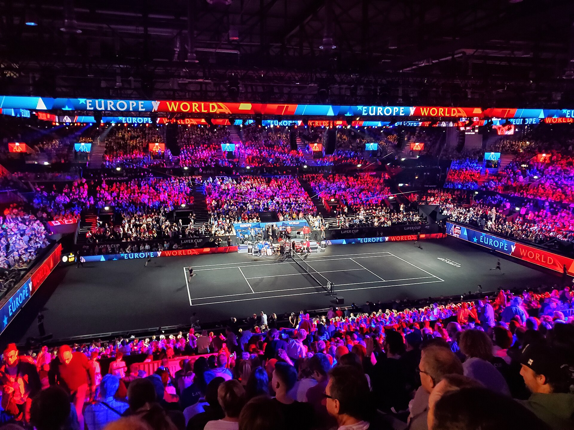 Quadra preta da Laver Cup com linhas brancas e arquibancadas iluminadas em vermelho e azul.