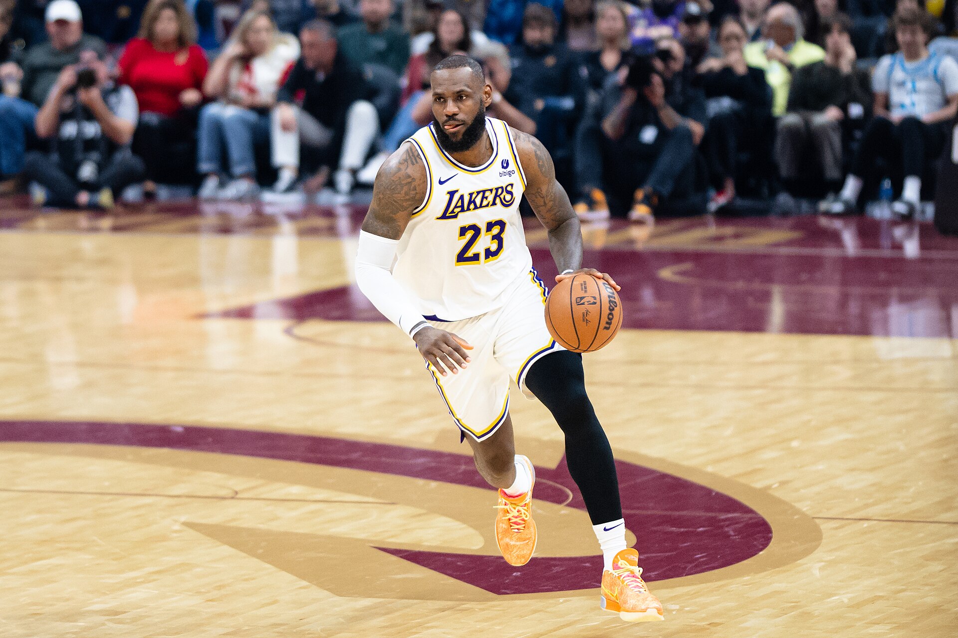 LeBron James com o uniforme branco do Los Angeles Lakers conduzindo a bola em uma quadra de basquete.
