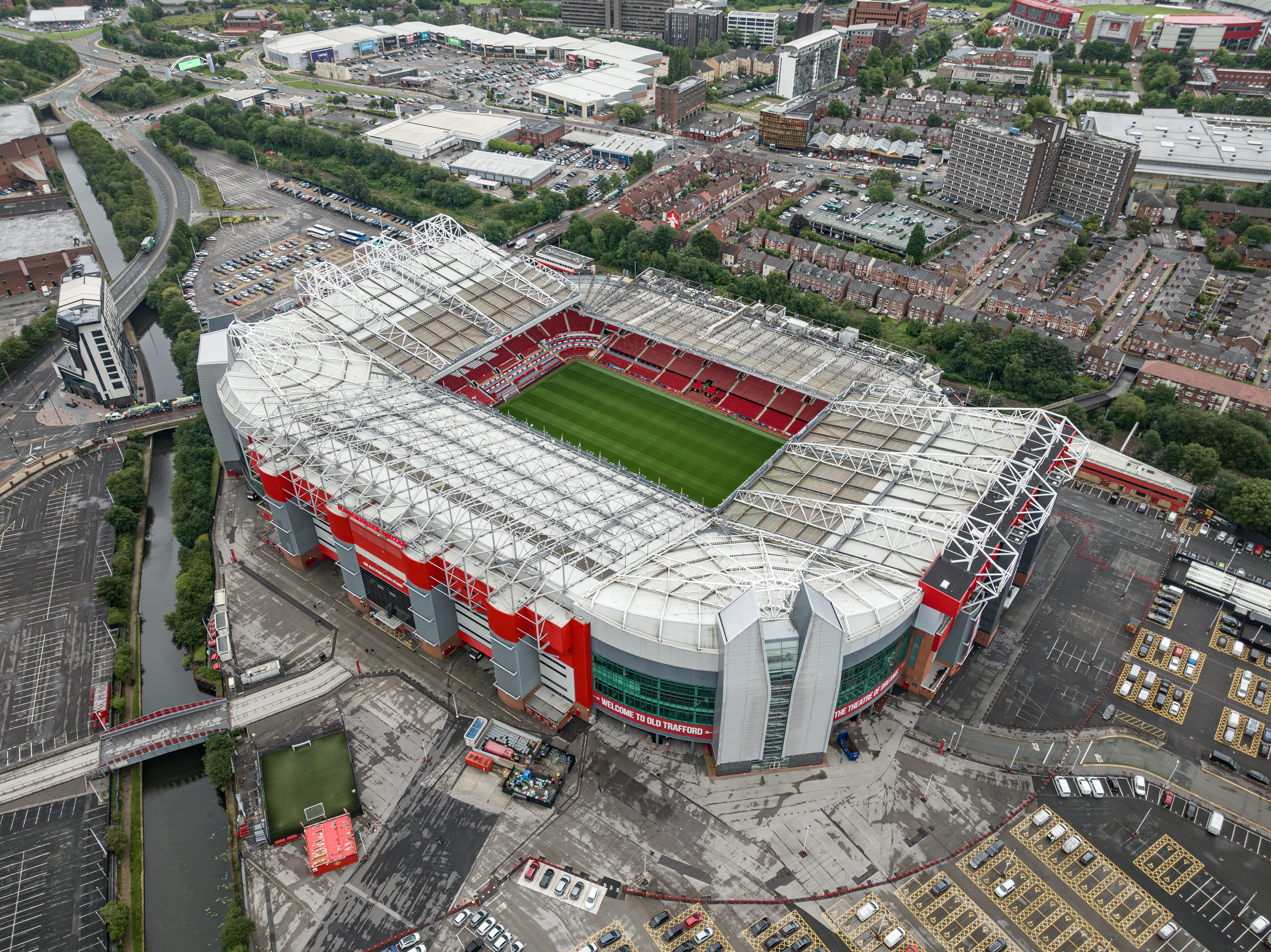 Old Trafford visto do alto com o estádio completo e área urbana adjacente.