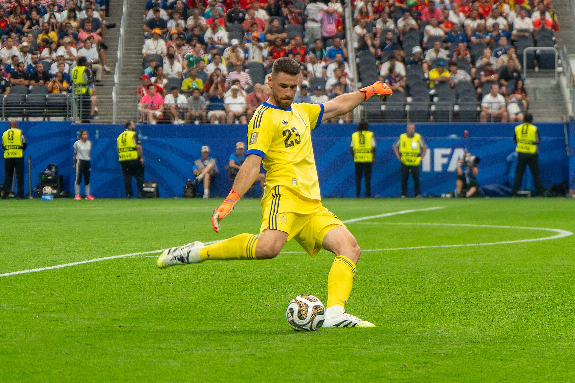 Unai Simón, de uniforme amarelo, chuta a bola em campo durante partida entre França e Espanha.